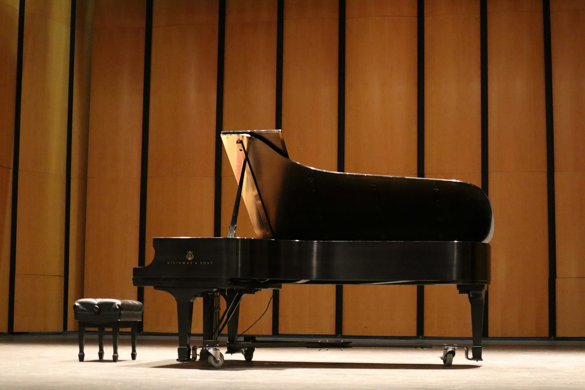 A grand piano on a warmly lit concert stage